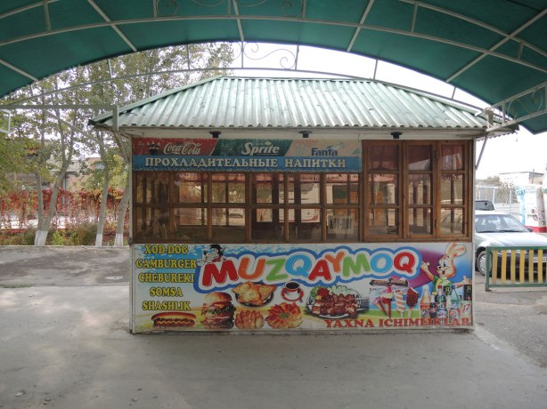 an empty hot dog stand in an amusement park in Bukhara, large pictures advertising what food it sells, hot dogs, hamburgers, fast food 