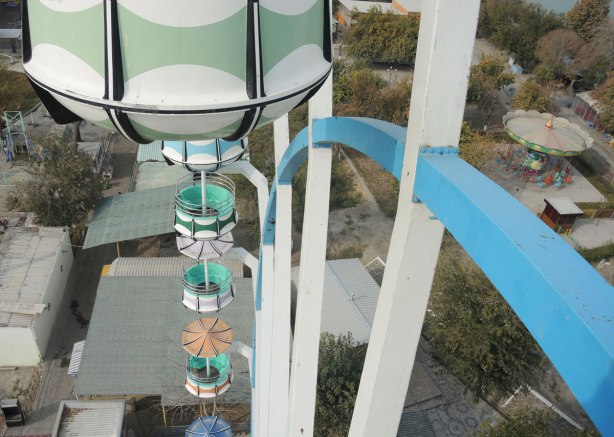 looking back from near the top of a ferris wheel, showing the pods (seats) of the ride, and the ground below. 