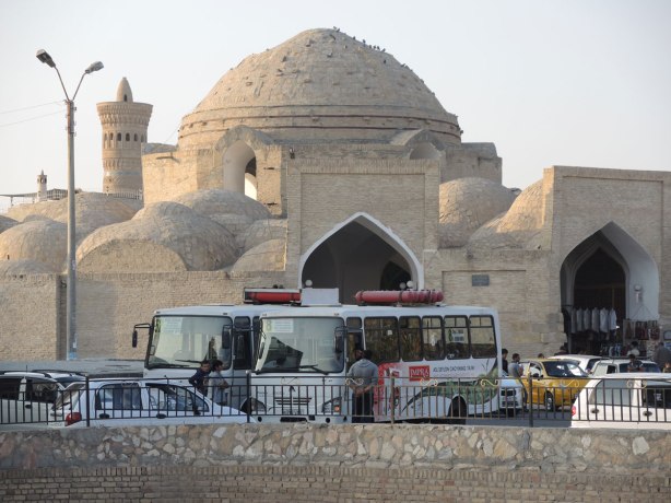 dome shaped building in the historic center of Bukhara with many buses parked in front, 
