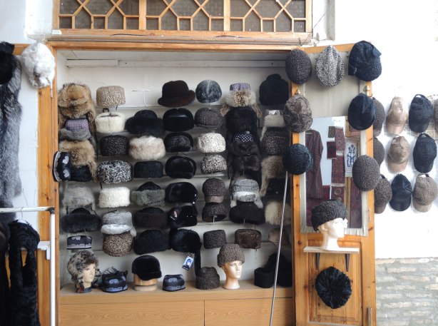 Against an outdoor wall, many fur hats for sale in Bukhara Uzbekistan