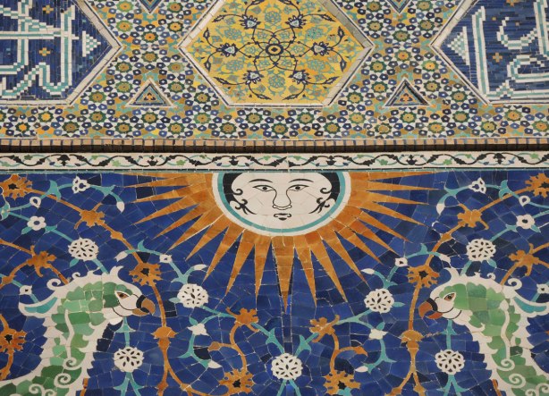 phoenix and sun made of mosaic tiles over the entrance of a madrassah in Bukhara, the Nadir Divan Begi Madrasah - close up picture of the face on the sun 