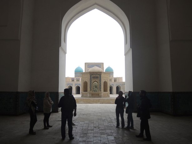a group of people inside the entrance to the Kalyan mosque, looking out over the courtyard in front of it. 