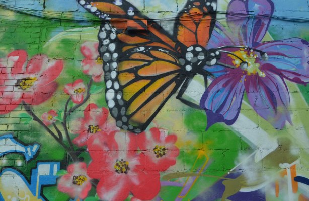 a monarch butterfly in a mural along with many pink and purple flowers 