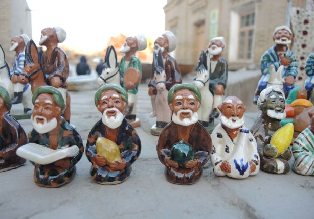a line of little ceramic figurines that are for sale at an outdoor vendor, old men with white beards and green hats