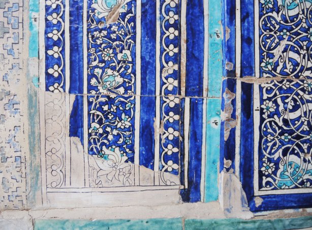 broken tile mosaics in blues and white, drawing on the wall to show where the missing tiles would go 