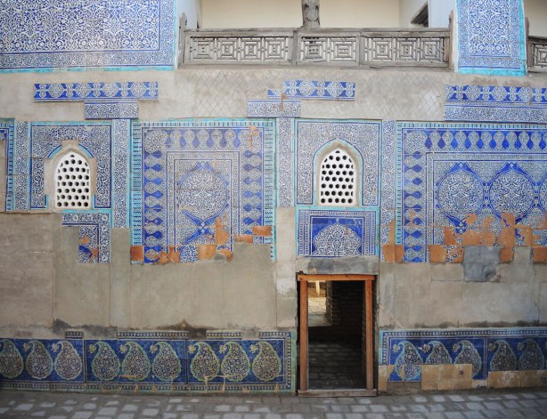 wall on an old mosque in Khiva, some of the mosaics are still there and some blank spaces on the wall where the tiles were 