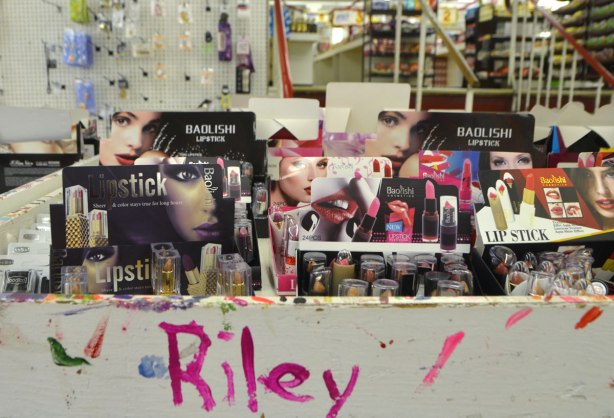 interior of Honest Eds store as it gets ready to close down. a bin of lipstick and other makeup. Someone has written the word Riley in pink lipstick on the side of the bin 