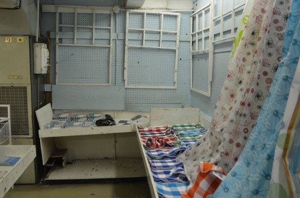 interior of Honest Eds store as it gets ready to close down. a few shower curtains on display as well as some checkered tea towels. The rest of the shelves and wall space are empty 