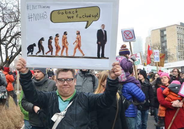 Womens March, toronto - a man holds up a sign that is a play on the evolution of man meme, as they walk upright they come to a figure of Donald Trump. The last man in the evolution chain turns around and says Go back, we fucked up. 