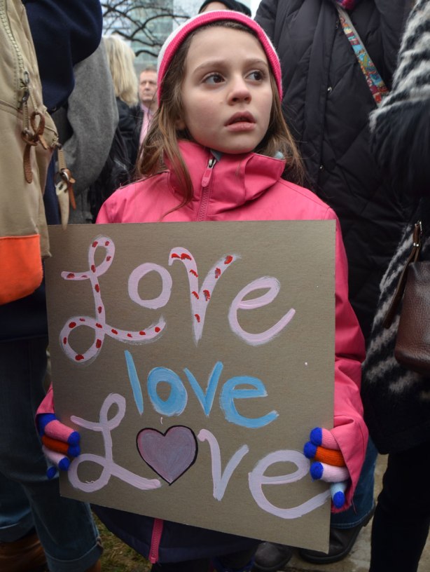 a young girl in pink holds a sign that says love love love. Womens March, toronto 