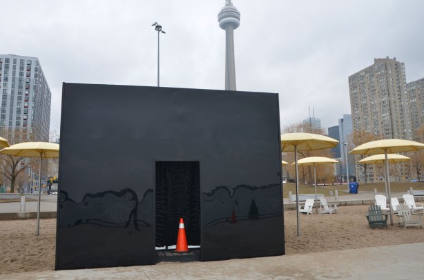 black box on a beach with muskoka chairs and yellow umbrellas, 