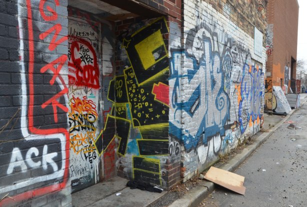 half of a large black lovebot painted in a doorway (one side of him). A black lovebot with yellow details and a red heart.