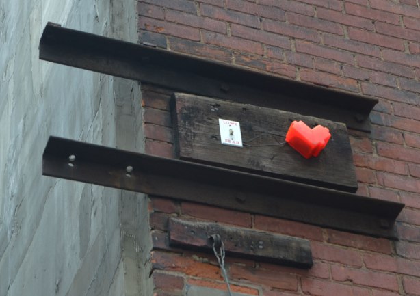high on a wall, a small 3D lovebot heart beside a light switch that is love on one side and fear on the other.
