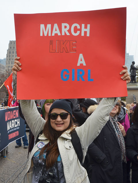 a woman holds up a red sign that says March like a girl, Womens March, toronto 
