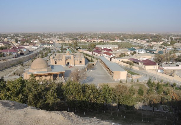 the view of Nurata from the hill where Alexander the Great built his fortress. low rise buildings, a mosque with a dome, a few trees, and the desert beyond.