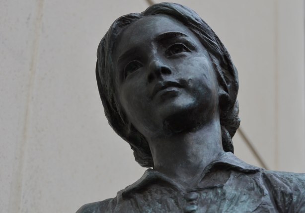 sculpture, Two Children of Toronto by Ken Lum in a downtownwalkway with a concrete bulding beside it, girl's face