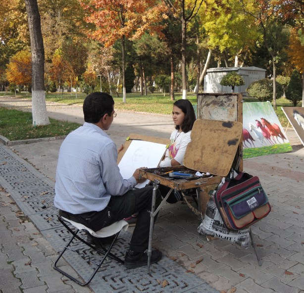 a man is drawing a portrait of a young woman, outdoors