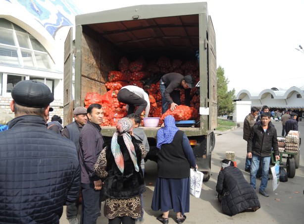 people buying bags of onions from the back of a truck