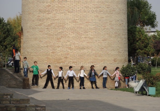 school children link hands to form a cirlce around the base of a minaret