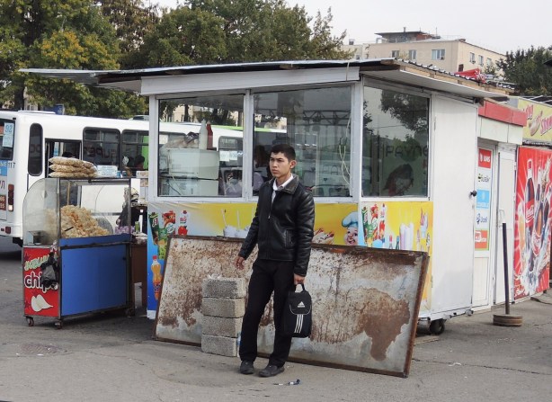 a boy waits for a bus at a bus stop