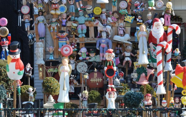 a massive collection of dolls, toys, stuffed animals and decorations fill a front yard of a house 