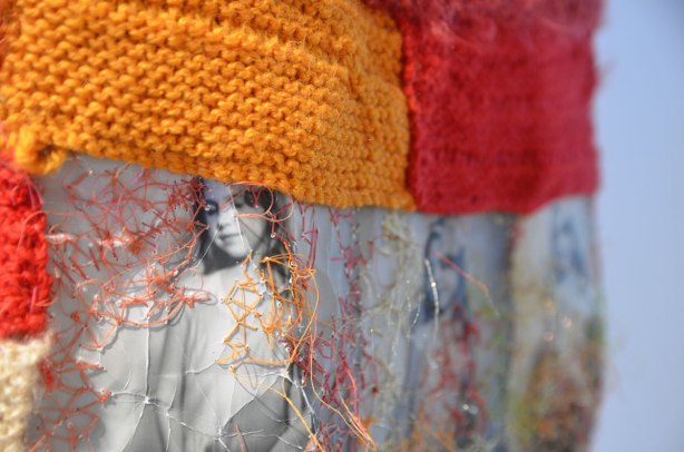 part of a dress made of black and white pictures printed on fabric, and knitted squares in orange and red yarn