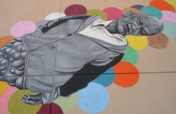 part of a larger mural by Troy Lovegates, an older man in black, white and grey floats as if he's asleep on coloured circular bubbles