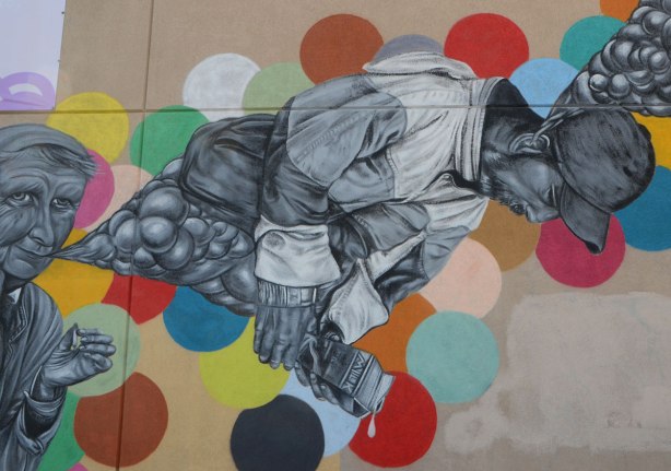 lovegates mural, people in grey tones, background of different coloured circles, man is horizontal, facing down, holding a dripping milk carton in his hand. 