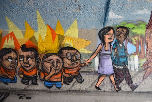 mural by elicser in the tunnel that is a railway underpass - a mother and father lead a group of noisy kids on a walk 