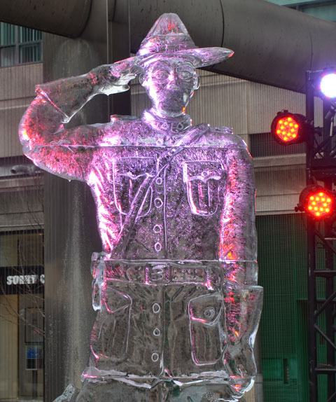a ice sculpture of a mountie standing at attention and saluting, light by pink and red lights, 