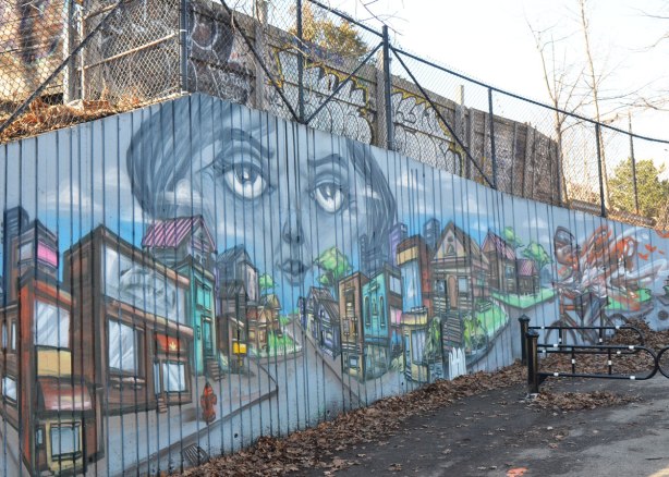 part of a larger mural by elicser in Monarch Park - a large woman's head and many buildings 