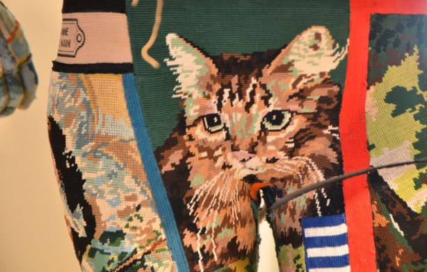  close up of part of a mannequin dressed in tight fighting fabric made of a patchwork of tapestry pieces. The piece shown in this image is of a brown cat 