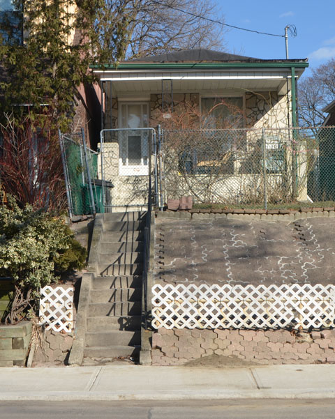 a small narrow one storey house. Many steps to get up the hill to the front door. The incline has been covered with patio stones. 