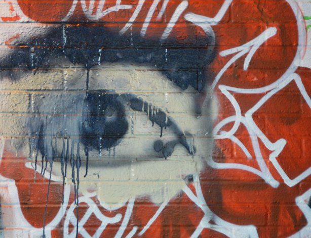 a black and white eye graffiti painting, smudged and with dripping paint, red background 