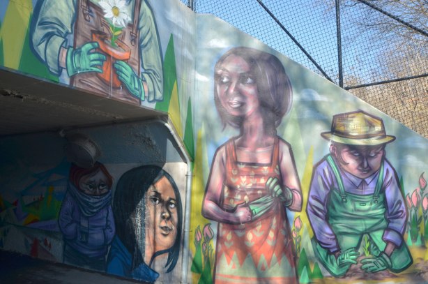 a mural by elicser on a railway underpass by the woodfield community rail garden, pictures of people gardening 