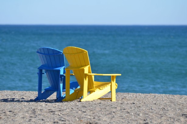 two empty muskoka chairs on the beach beside Lake Ontario on a sunny February day 