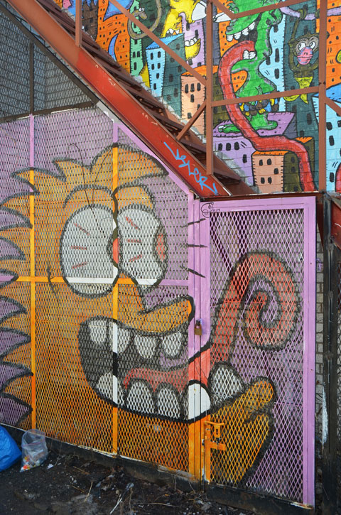 face of a creature with bulging eyeballs, a large oen mouth showing many big rounded white teeeth, and a long tongue that can make a spiral as it curls back on itself. 