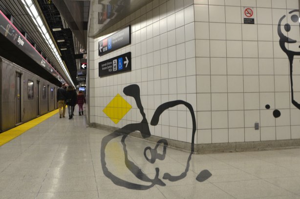 art on a subway platform, a line drawing of a very large apple that has been cut in half, on the wall and floor of the station