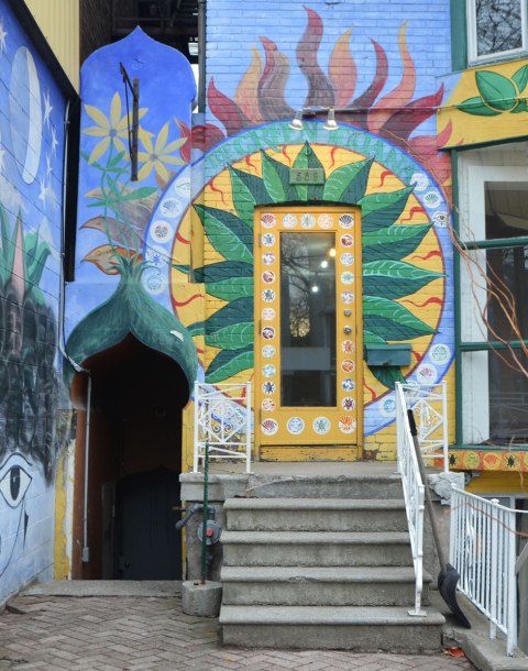 two doors on a brightly painted buidling. a flower is painted around the door, blue paint, 