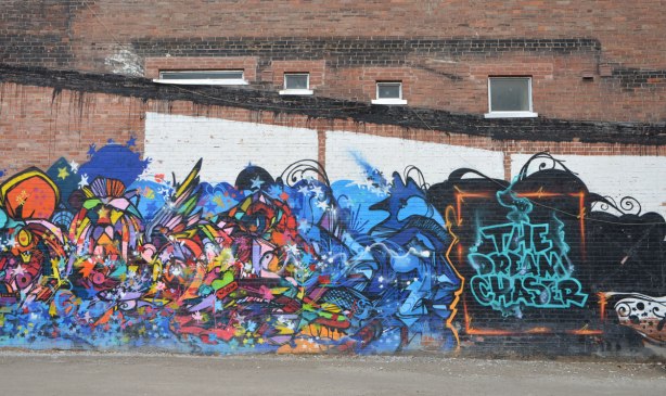one end of a colourful mural with many shapes and colours, with the title of the mural, The Dream Chaser