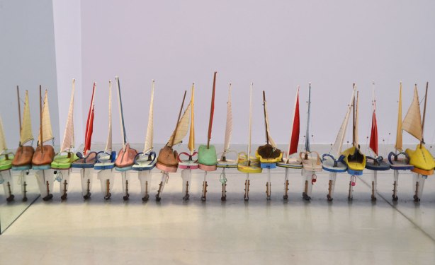 a line of little sailboats on the floor, all parallel to each other, the base of the boat (hull) is a flip flop or sandal. 