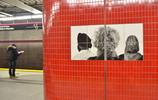 pillar covered in red tiles and with a black and white photo of the back of three peoples head, a man with a turban and a woman in a head scarf and someone with curly hair.