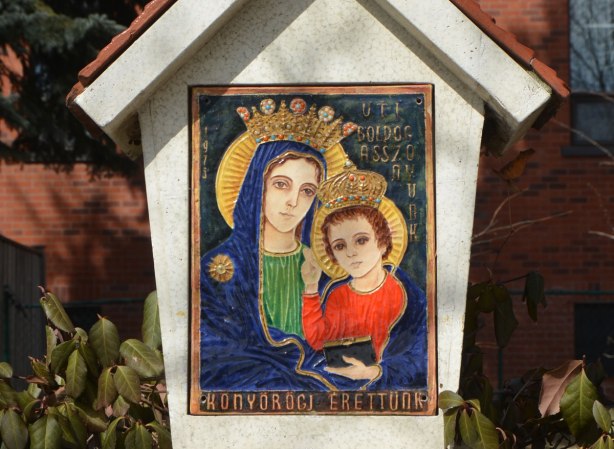 small picture of Mary and baby Jesus in bright colours, on a small shrine in front of a church 