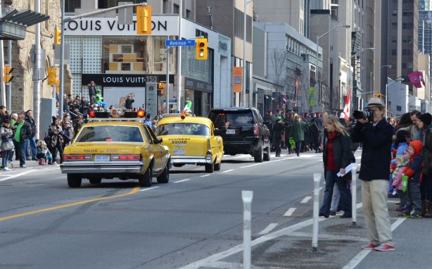 two old yellow police cars in the St. Patricks day parade