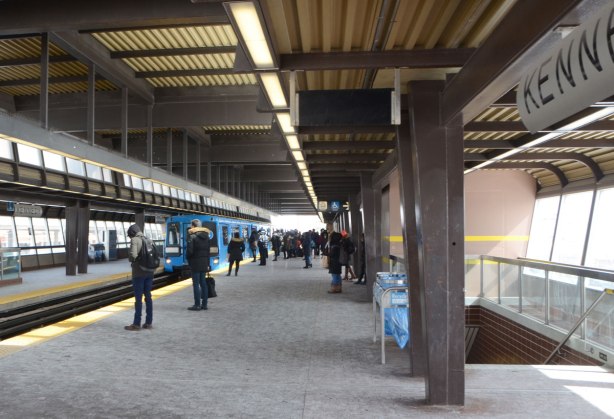 platform at Kennedy SRT station with people waiting as a blue train arrives