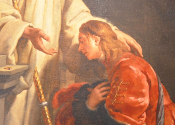 part of a religious painting of a young man in a red robe kneeling before another man in white who has one hand on the young man's shoulder. 