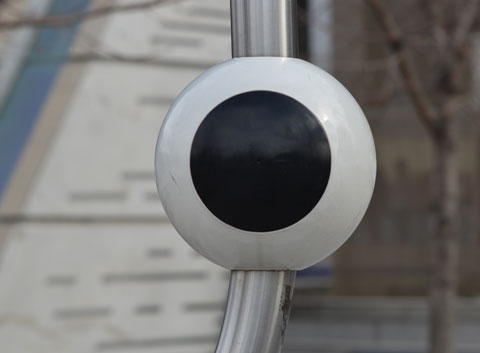 a large white sphere with a black circle in the middle, on a metal pole. Background is out of focus 