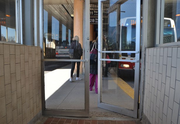 doors to bus platform at Davisville station, bus platform, are slightly ajar, a bus has just pulled up (and facing the camera) and people are getting ready to get on it. 