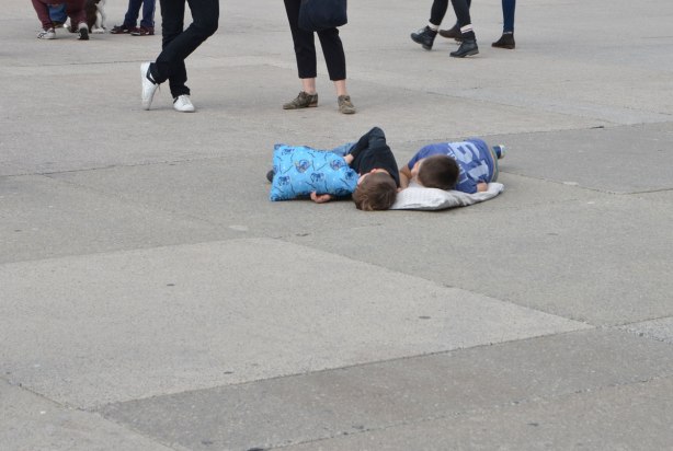 two boys lie on pillos on the concrete ground of Nathan Phillips Square