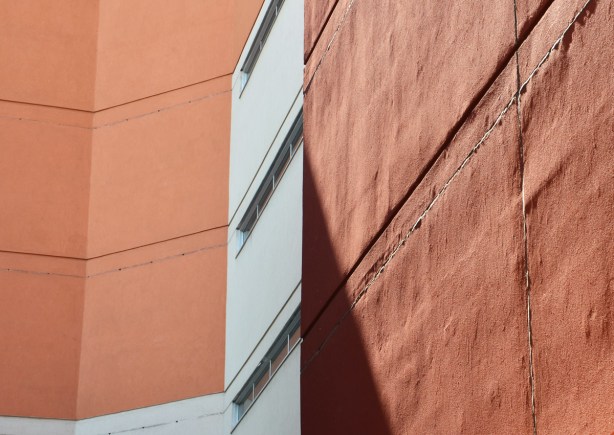 on an angle, rusty brown coloured wall with horizontal windows on a white section 